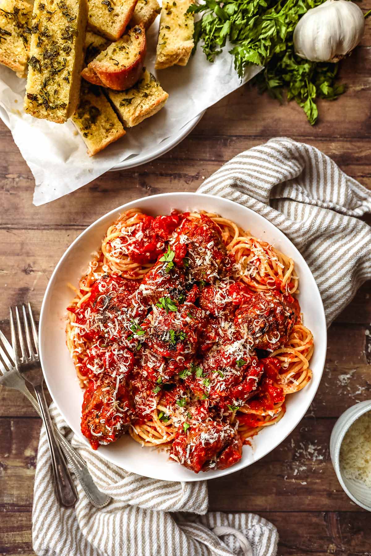 Spaghetti and Meatballs in a bowl with parmesan and parsley topping and fork