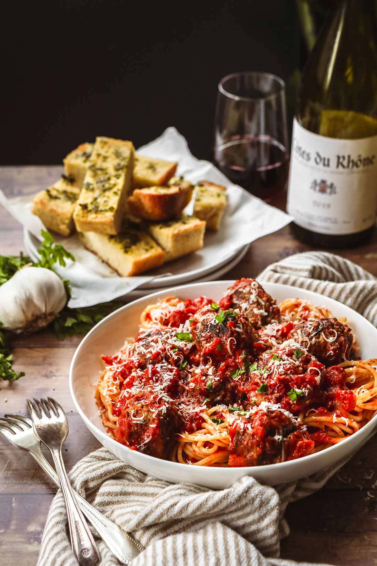 Spaghetti and Meatballs in a bowl with parmesan and parsley topping and fork