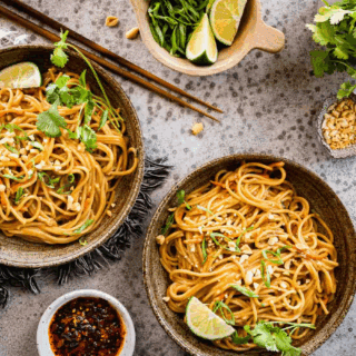Two bowls of noodles with garnishes and chopsticks