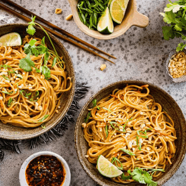 Two bowls of noodles with garnishes and chopsticks