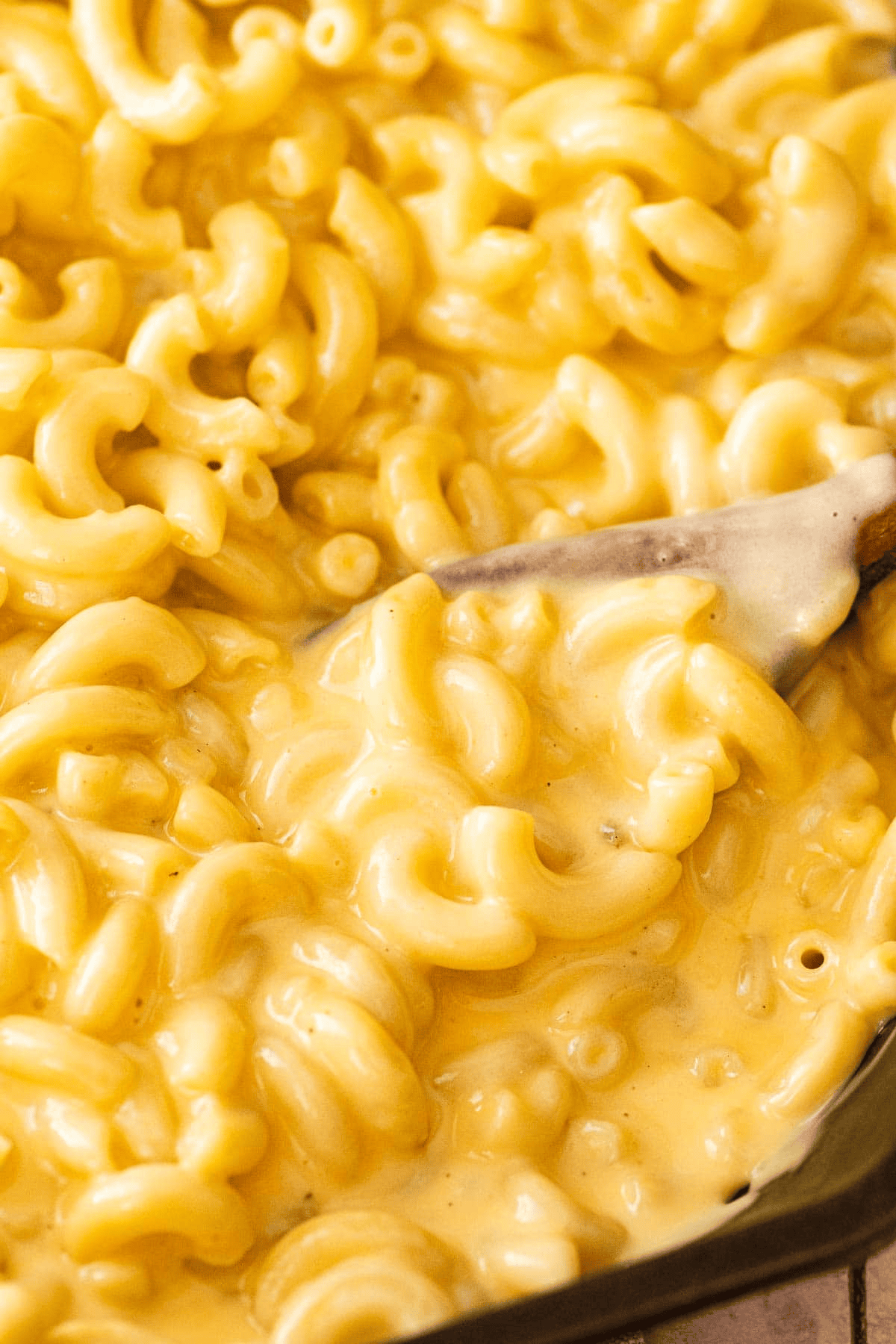 Wooden spoon stirring ultra creamy mac and cheese