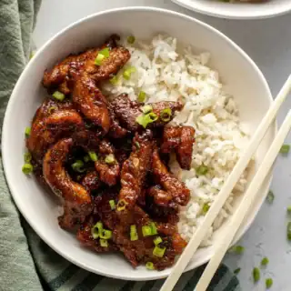 Bowl of fried and saucy chicken with rice.