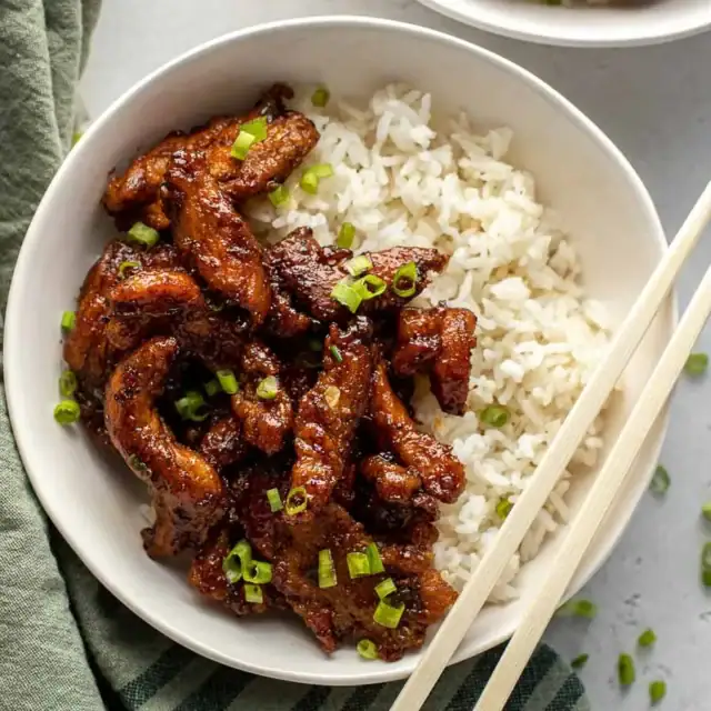 Bowl of fried and saucy chicken with rice.