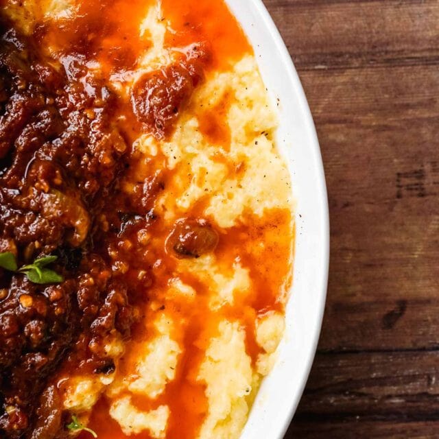 Baked Creamy Polenta in bowl with meat and sauce