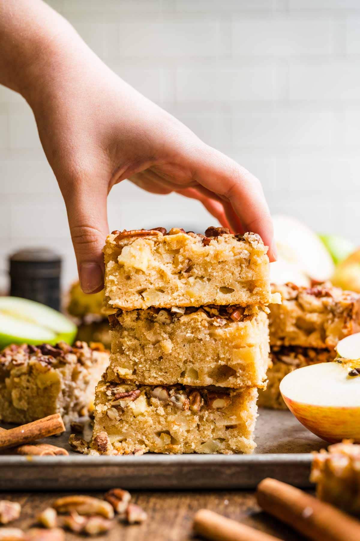 Apple Brownie Bars three in a stack with hand grabbing top bar