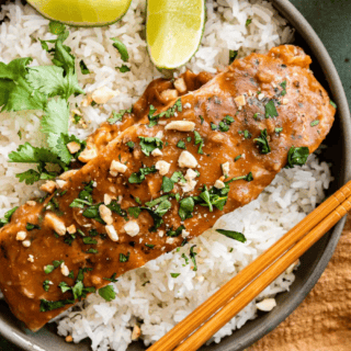 Salmon with Peanut sauce on top of rice with lime and chopsticks