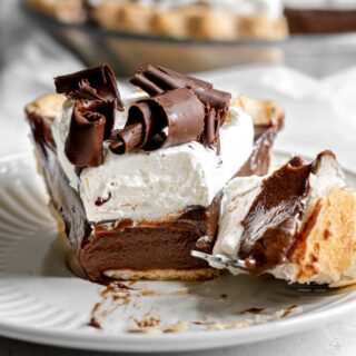 Chocolate Cream Pie with whipped cream and chocolate shavings on serving plate with fork