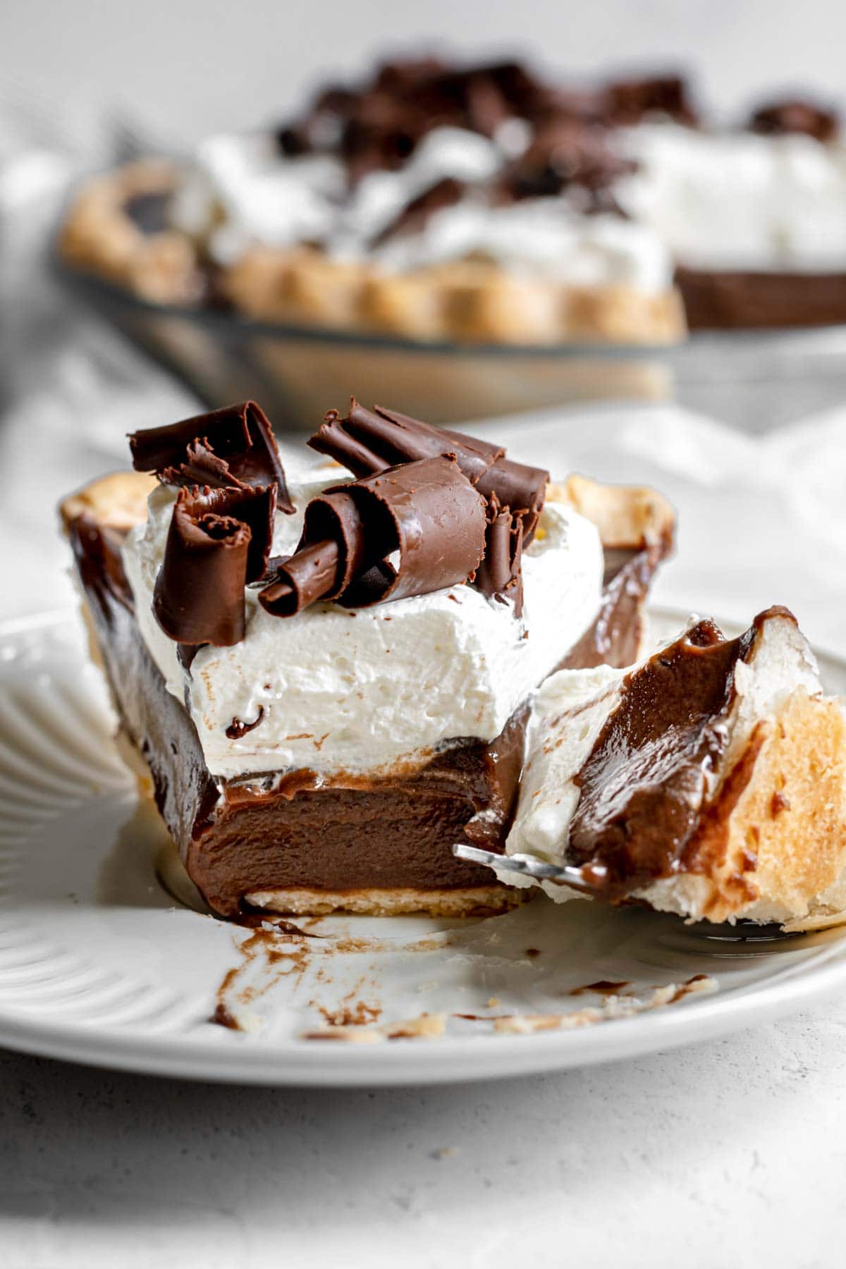 Chocolate Cream Pie with whipped cream and chocolate shavings on serving plate with fork