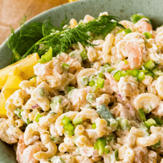 silky seafood noodles with veggies in a bowl with a lemon slice