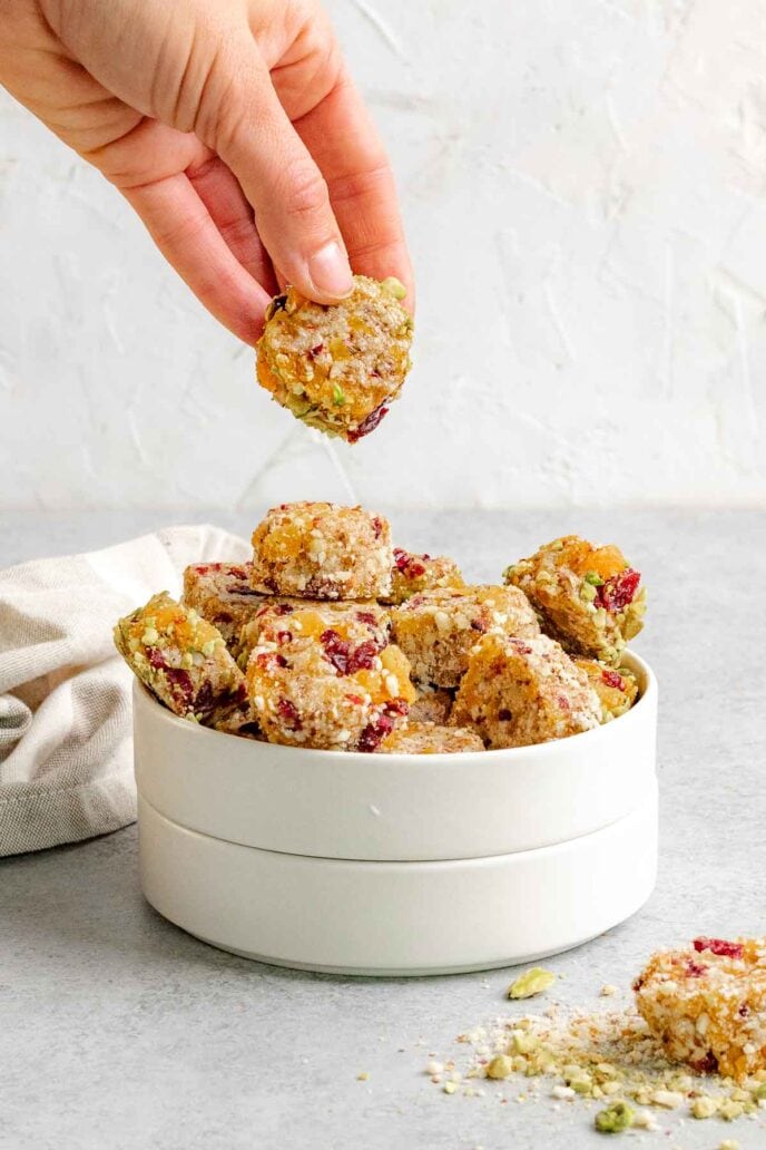 Fruit Almond Bites in Bowl with hand holding bite