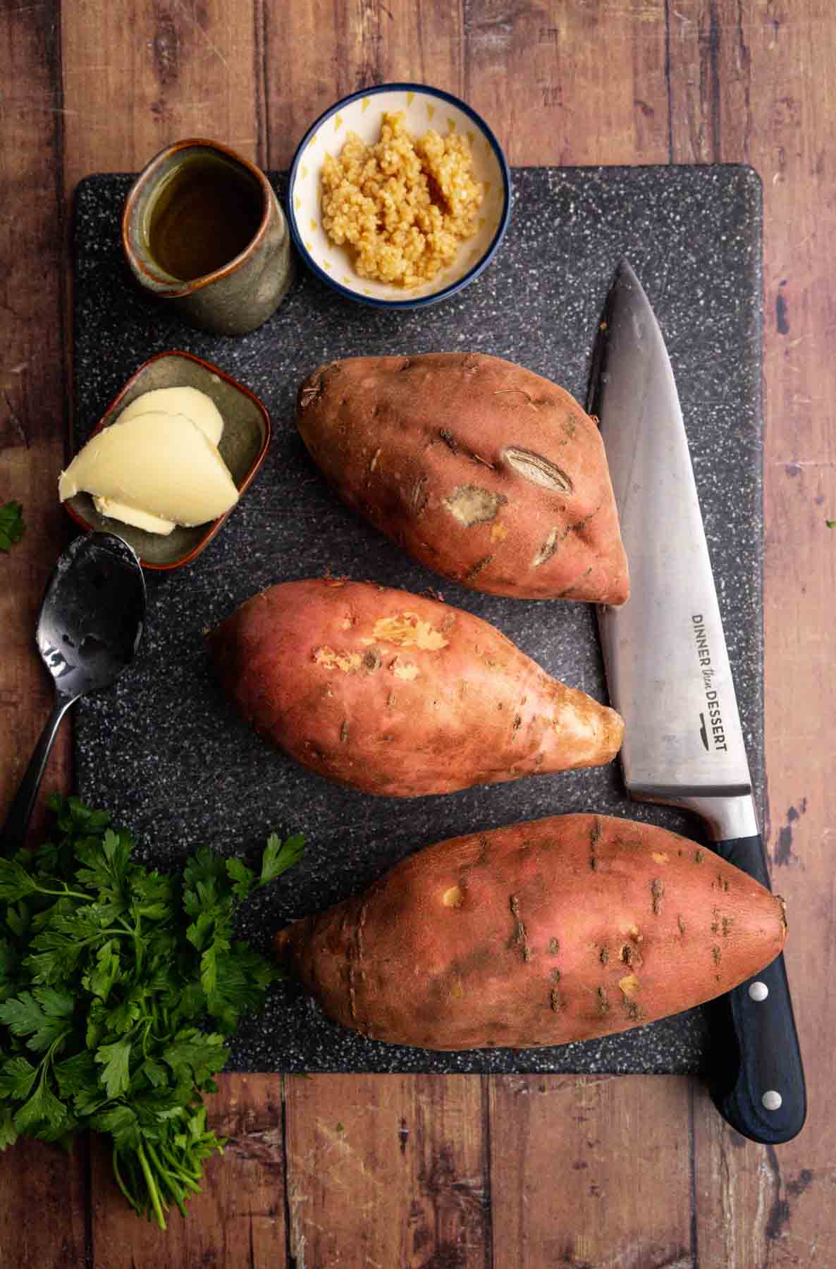 Garlic Butter Roasted Sweet Potatoes whole sweet potatoes, knife, and ingredients on cutting board