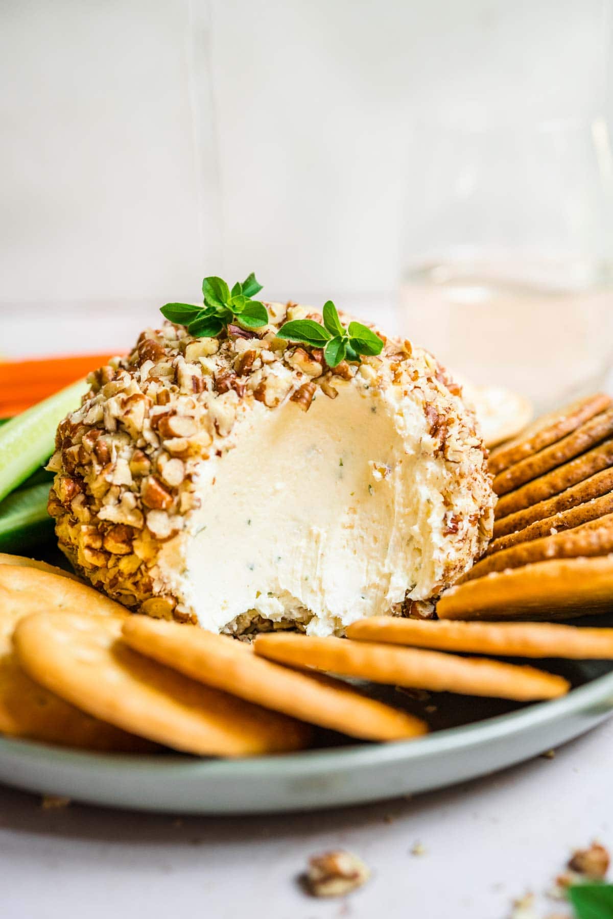 Garlic Parmesan Cheese Ball with scoop taken on serving plate with crackers and veggies