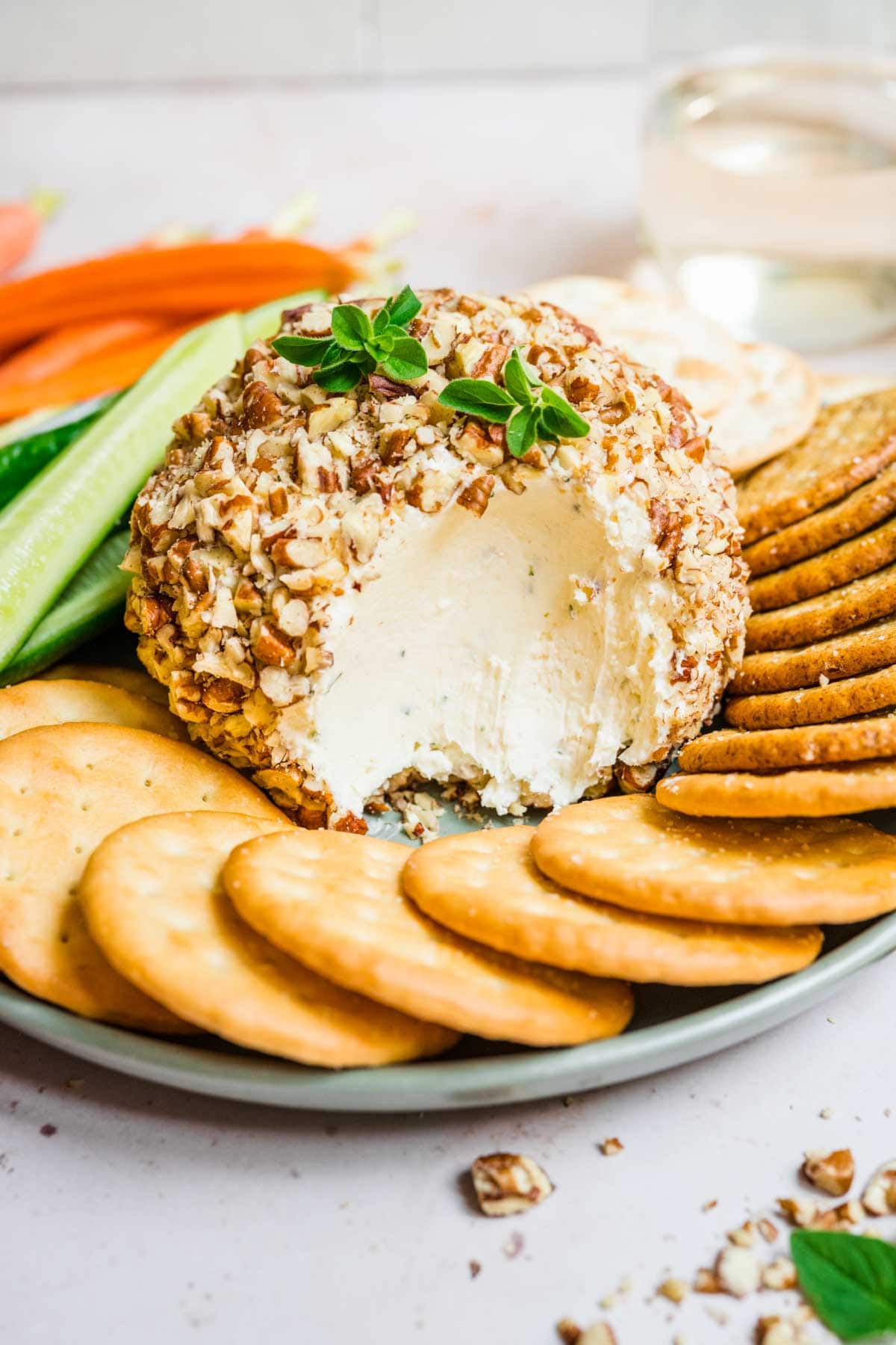 Garlic Parmesan Cheese Ball with scoop taken on serving plate with crackers and veggies