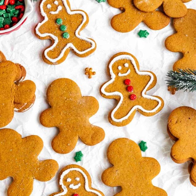 Gingerbread Men being decorated on top of white parchment paper.