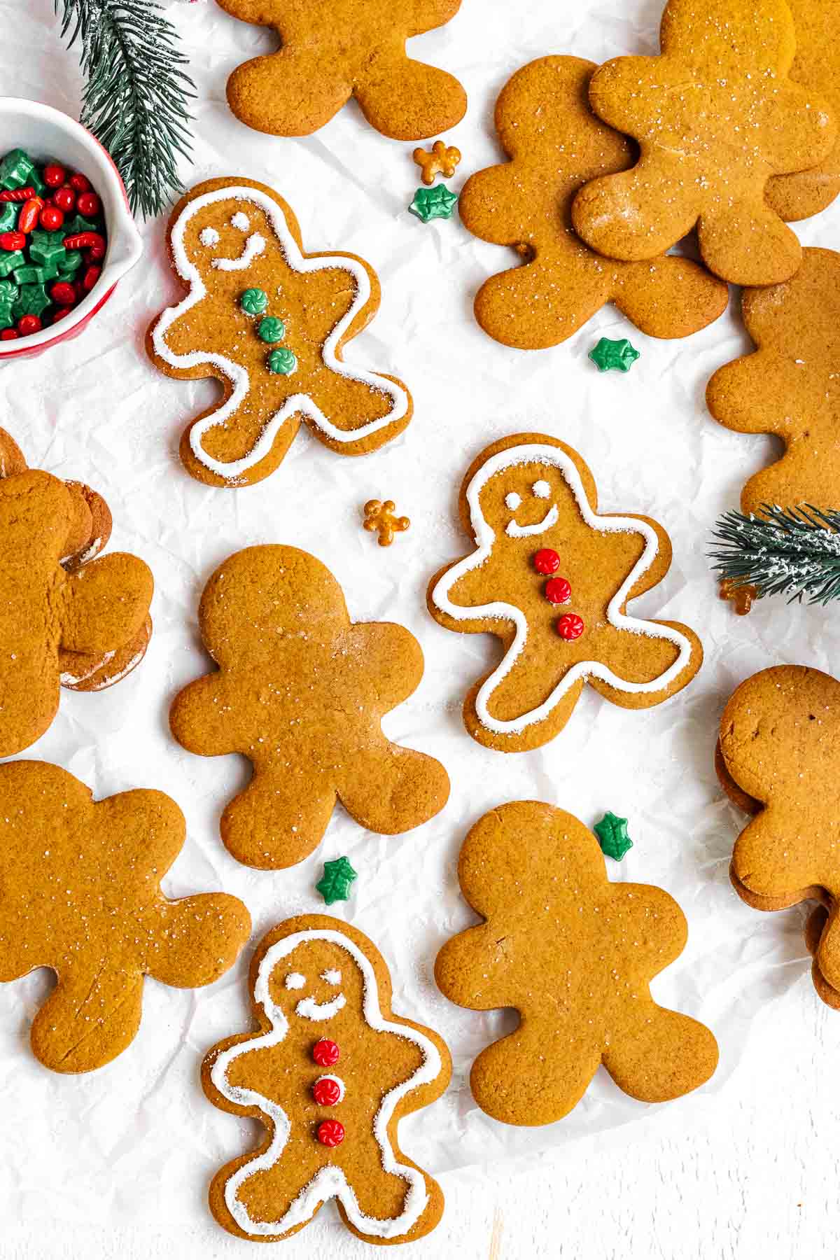 Gingerbread Men being decorated on top of white parchment paper.