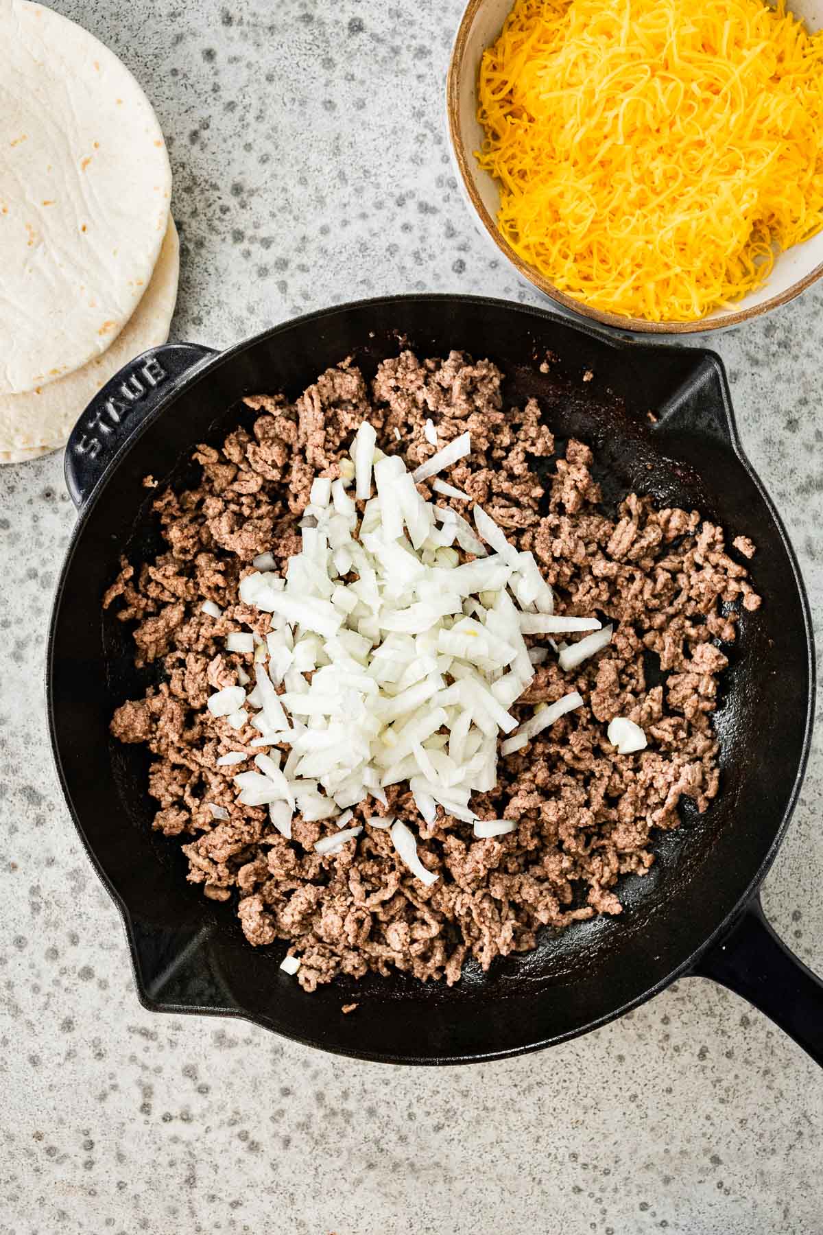 Ground Beef Soft Tacos cooked beef in skillet with raw onions on top