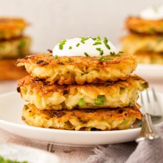 stack of three cooked potato pancakes with sour cream and chives garnish 1x1