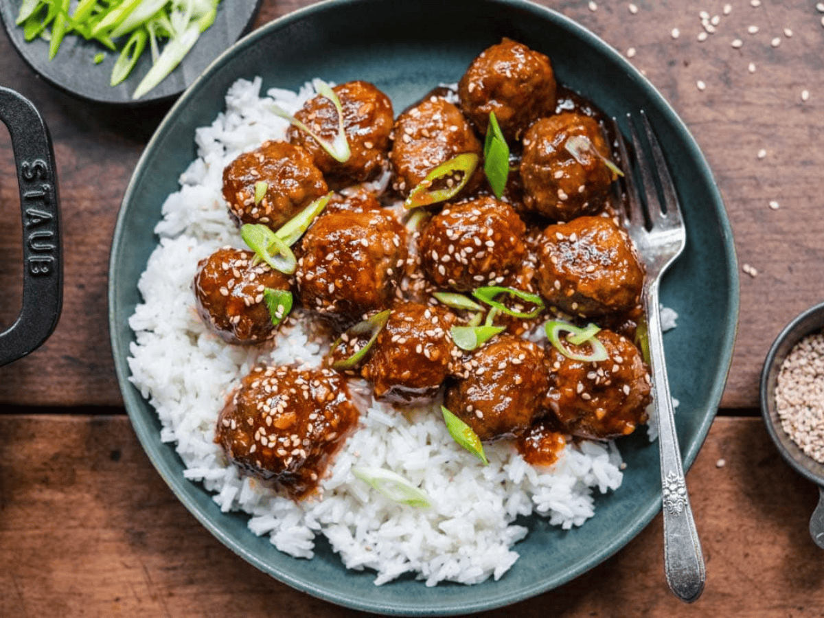 glazed meatballs on a bed of rice on plate with fork