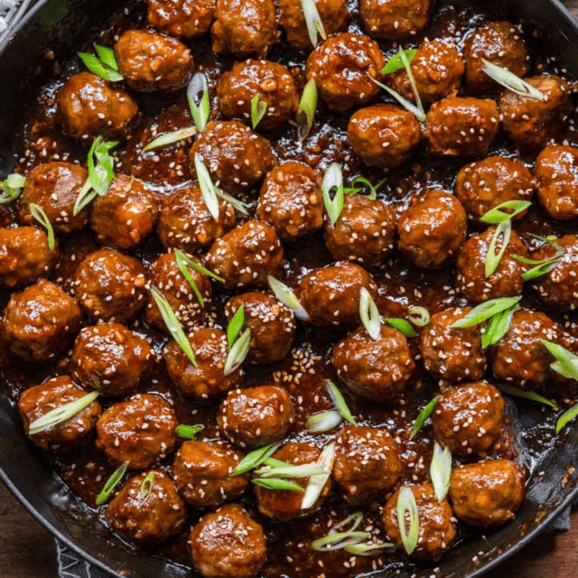 glazed meatballs with green garnish in a cooking pan