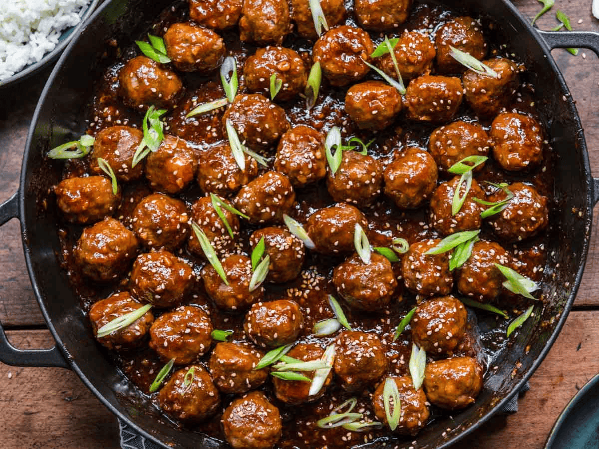 glazed meatballs with green garnish in a cooking pan