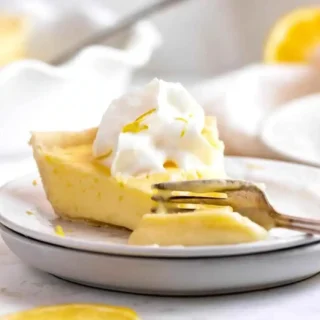 side view of pie being cut with a fork with whipped cream on top