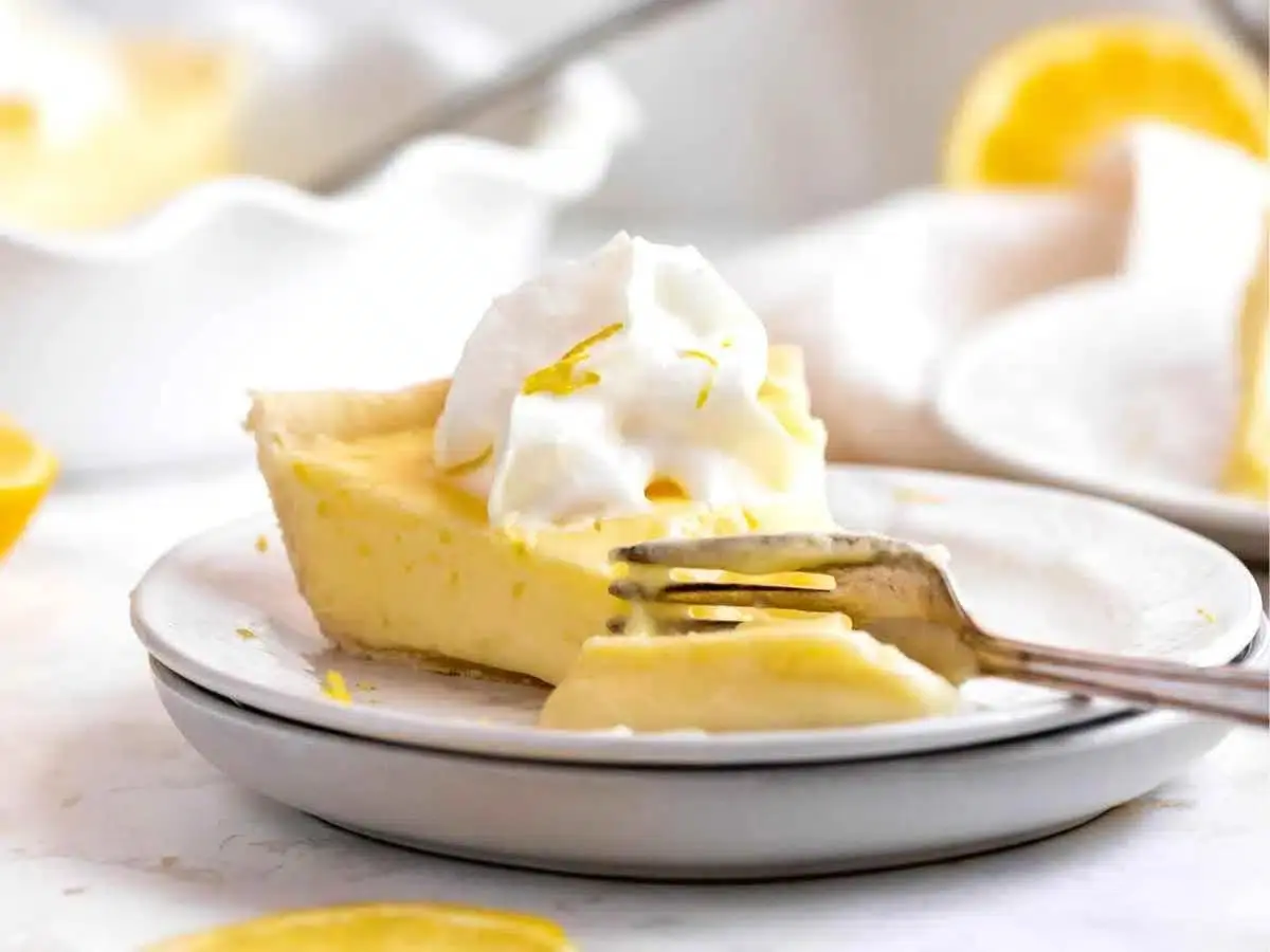 side view of pie being cut with a fork with whipped cream on top