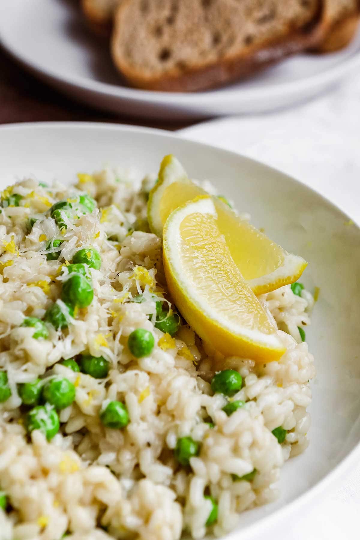 Lemon Parmesan Pea Risotto plated with lemon wedge garnish