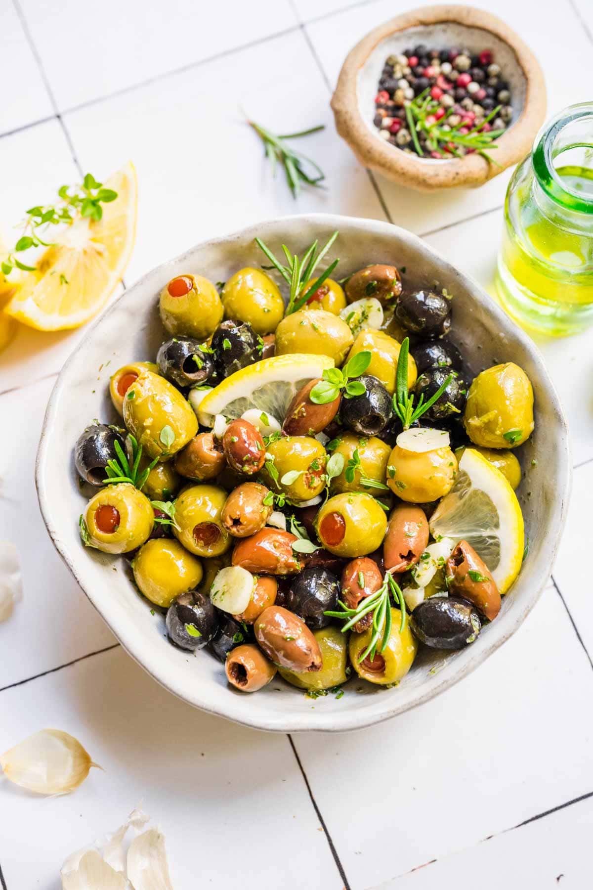 Marinated Olives olives in bowl with fresh herb and lemon garnishes