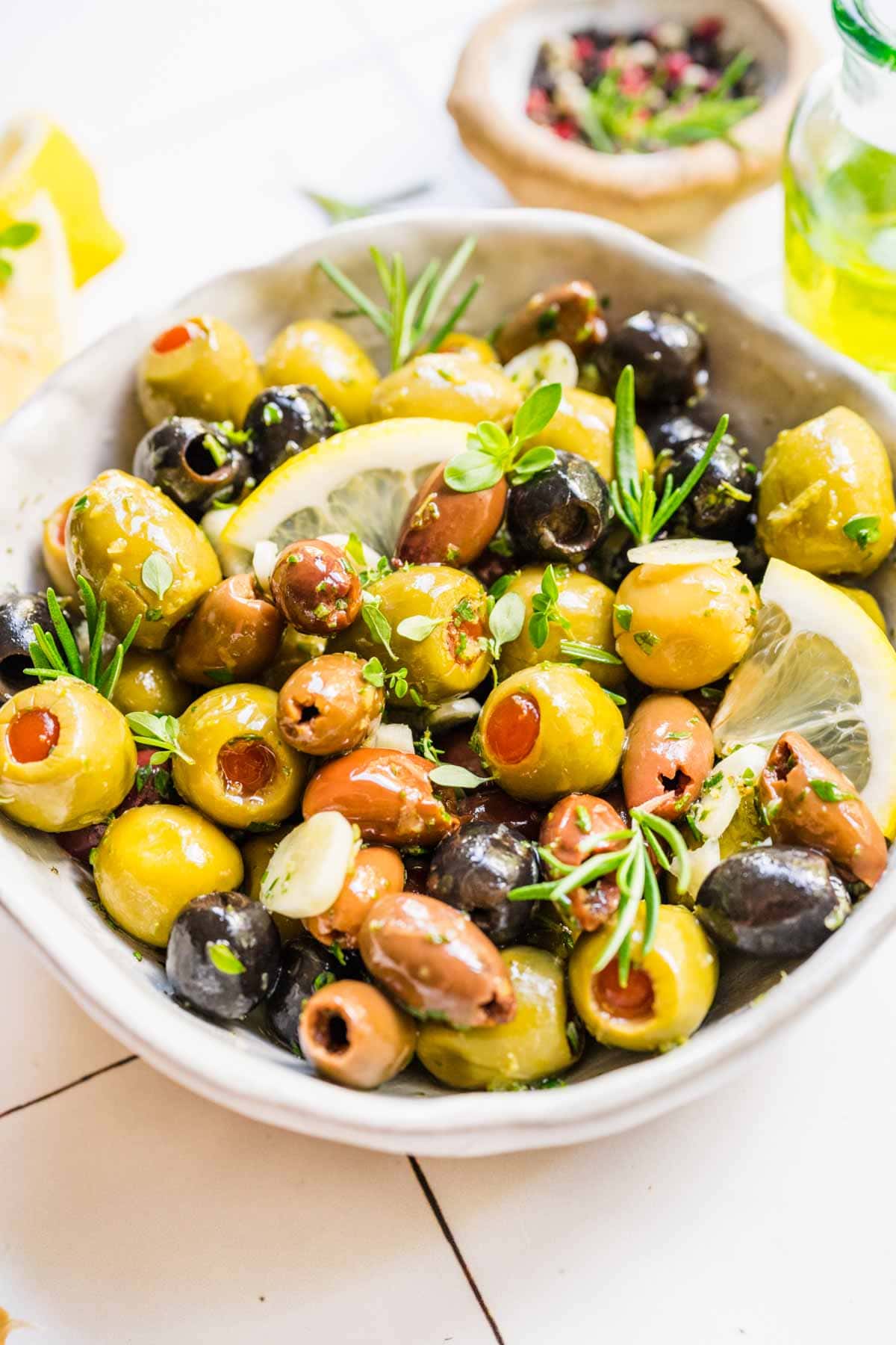 Marinated Olives olives in bowl with fresh herb and lemon garnishes