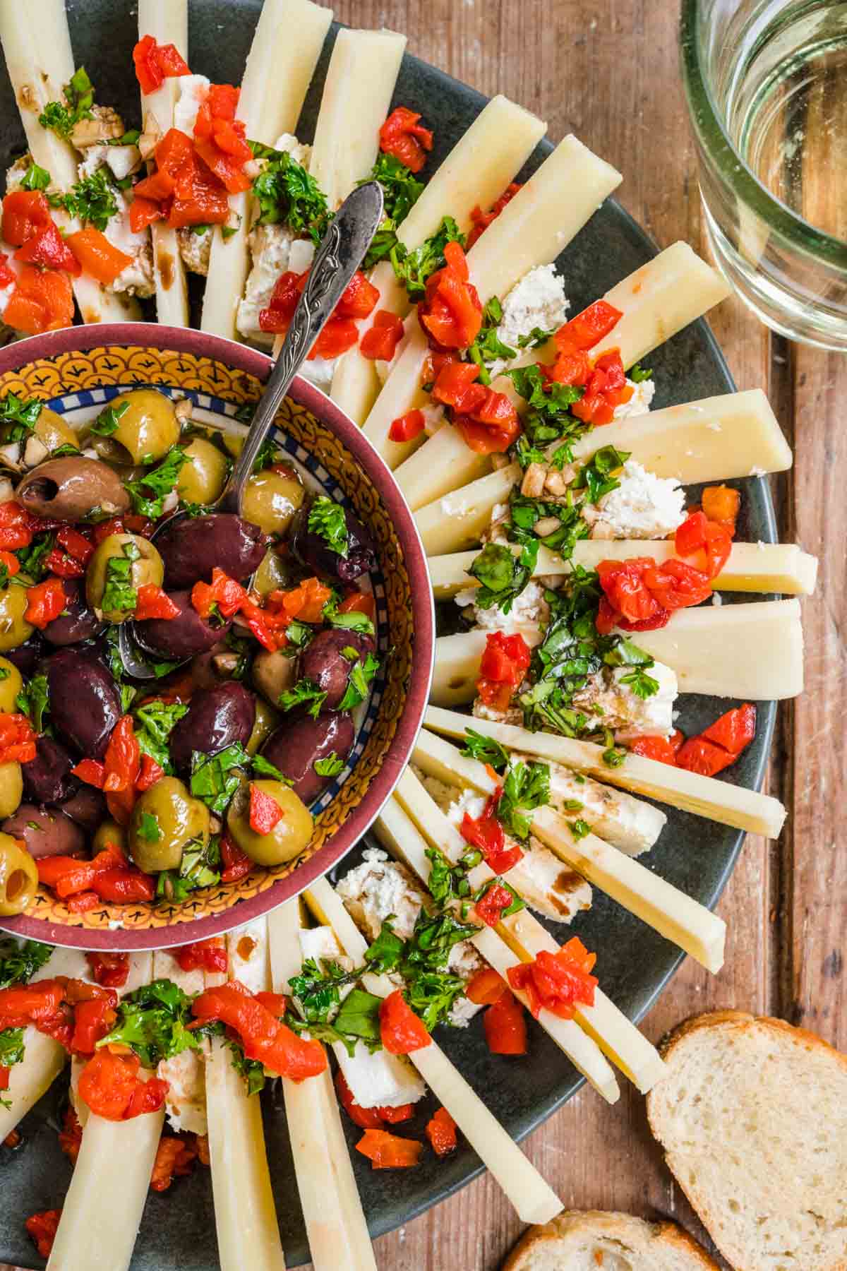 Olive and Cheese Ring on serving platter with olives in center and cheeses arranged around, topped with fresh herbs and pimentos