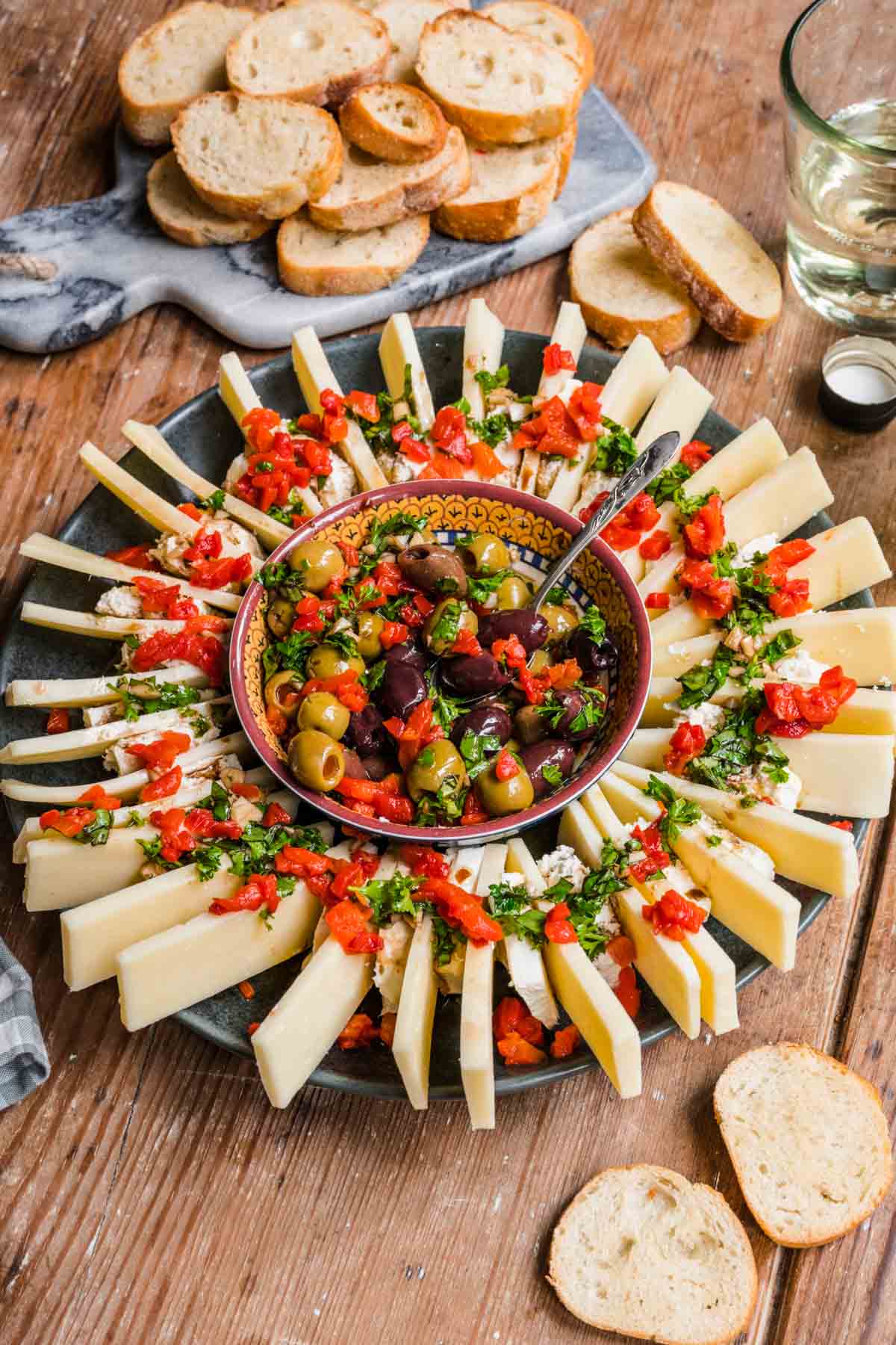 Olive and Cheese Ring on serving platter with olives in center and cheeses arranged around, topped with fresh herbs and pimentos