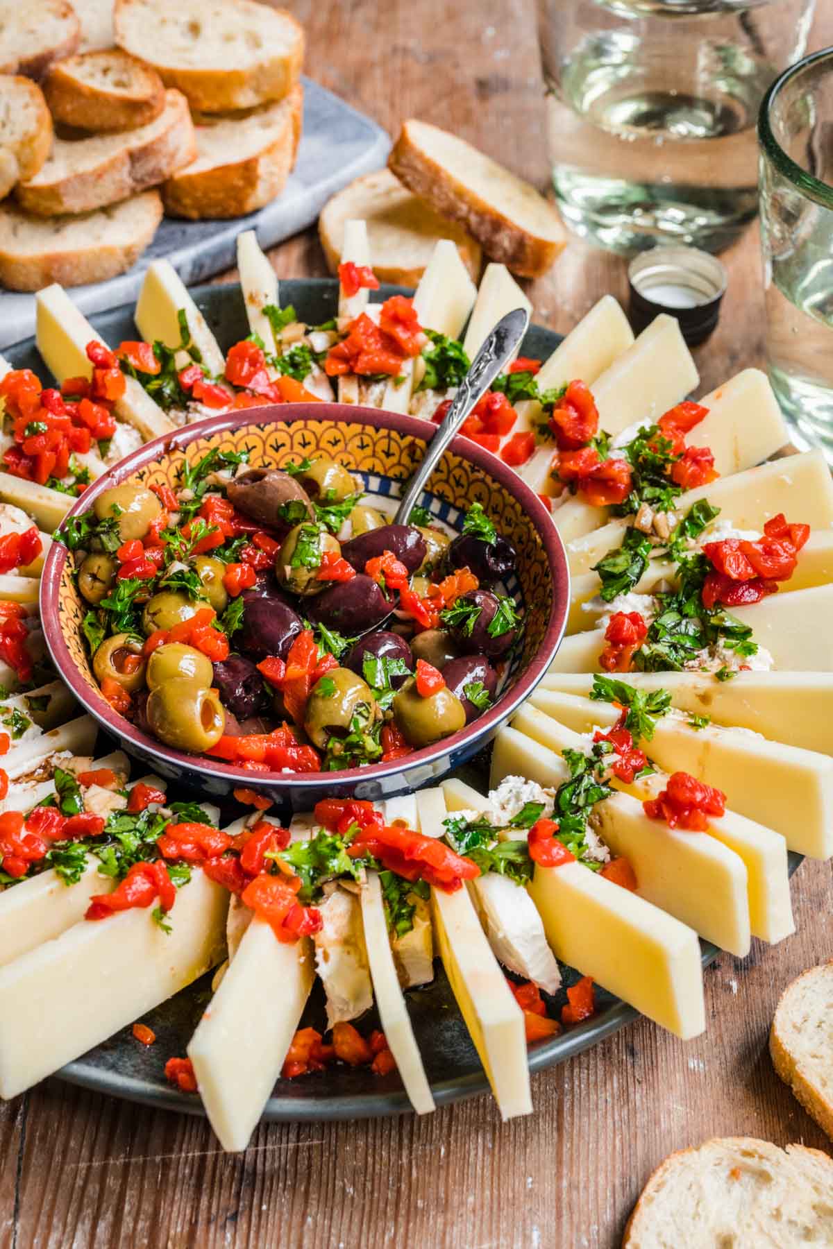 Olive and Cheese Ring on serving platter with olives in center and cheeses arranged around, topped with fresh herbs and pimentos