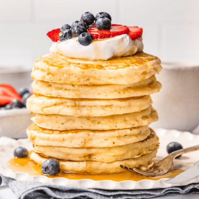 Stacked hotcakes on a plate with toppings ready to eat
