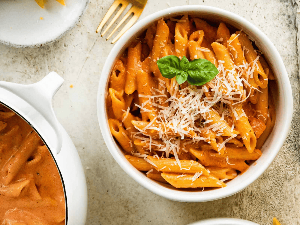 pasta in a bowl with pot of pasta on side