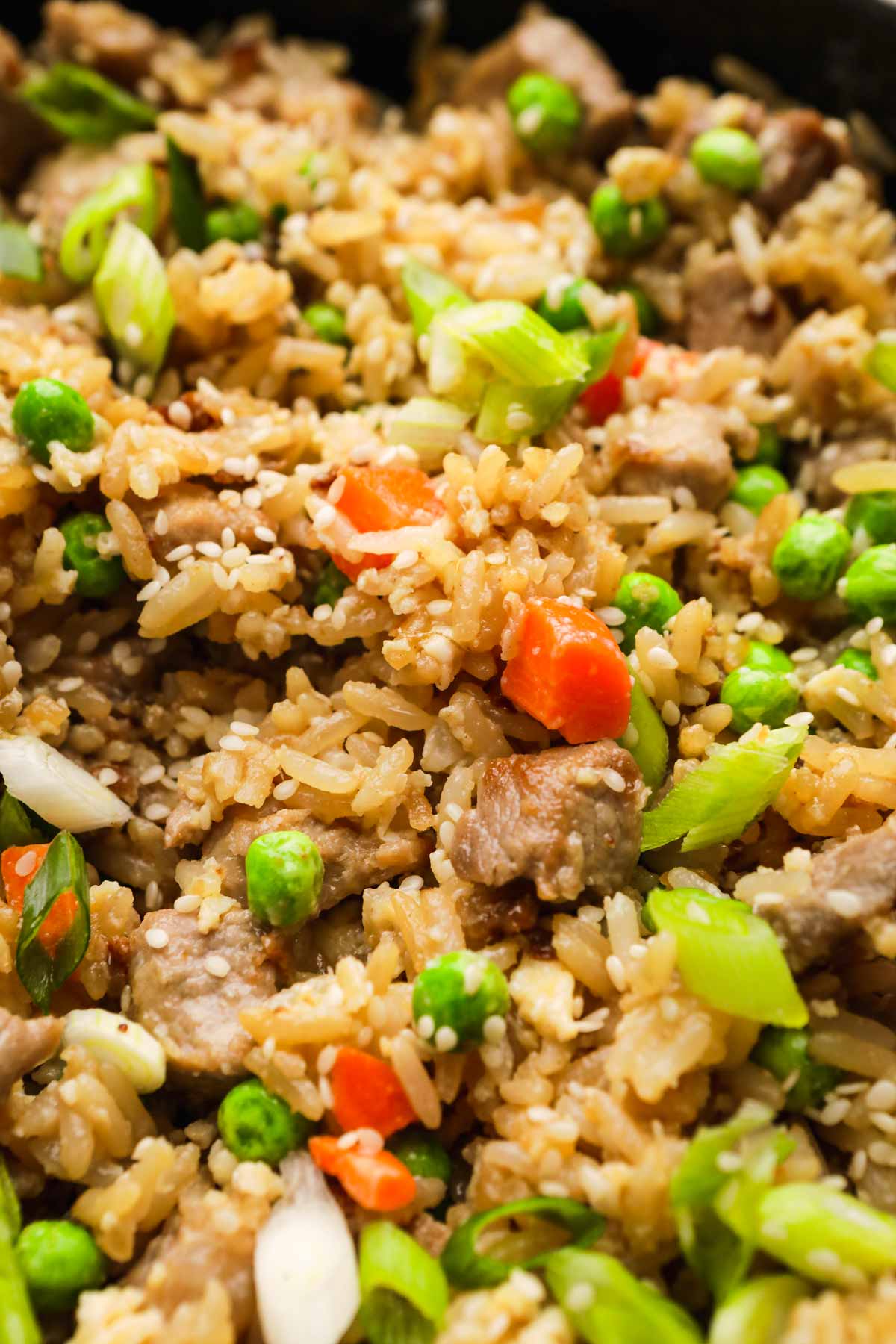 Pork Fried Rice in skillet with vegetables, egg, and sesame seed garnish