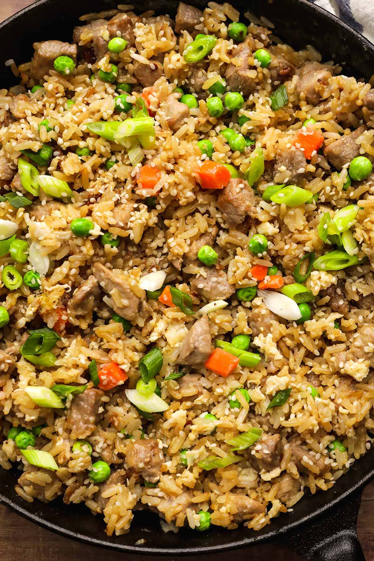 Pork Fried Rice in skillet with vegetables, egg, and sesame seed garnish