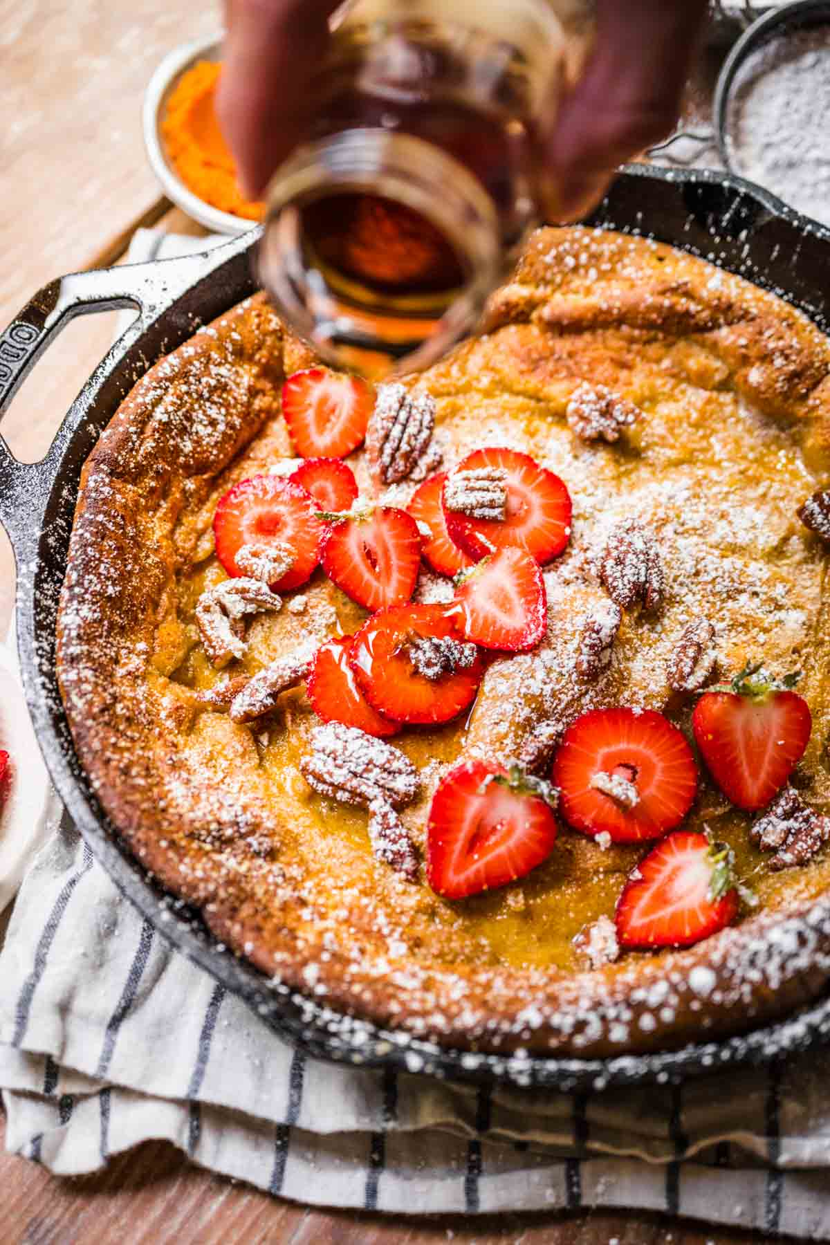 Pumpkin Dutch Baby Pancake baked in skillet with strawberries and powdered sugar on top