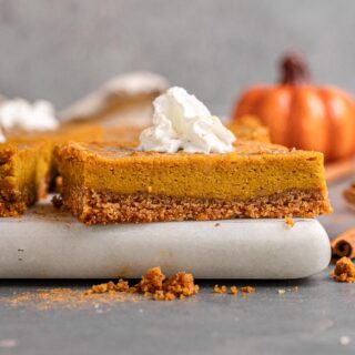 Pumpkin Pie Bar served with whipped cream on a cutting board.