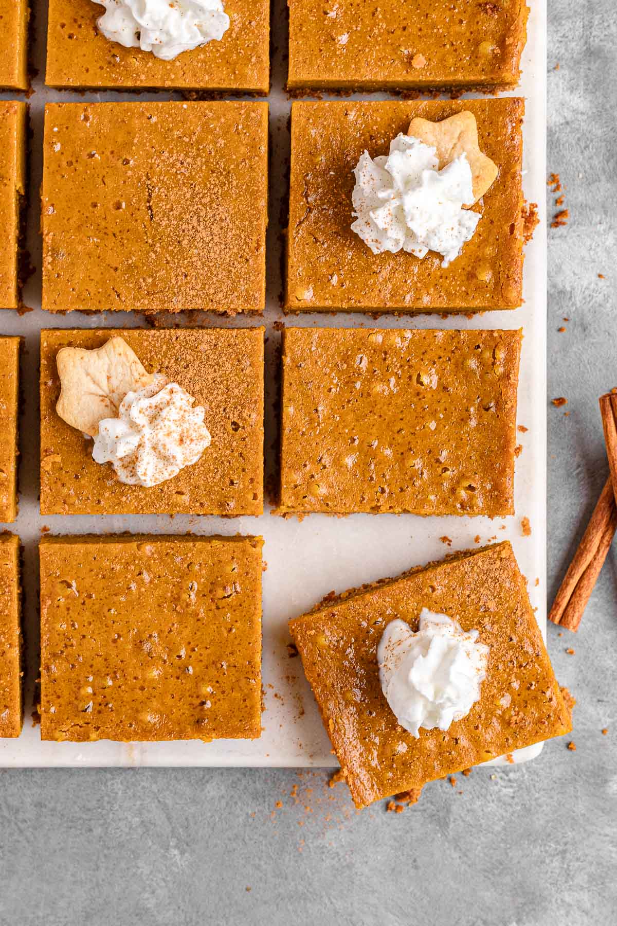 Pumpkin Pie Bars cut into squares on cutting board with whipped cream topping