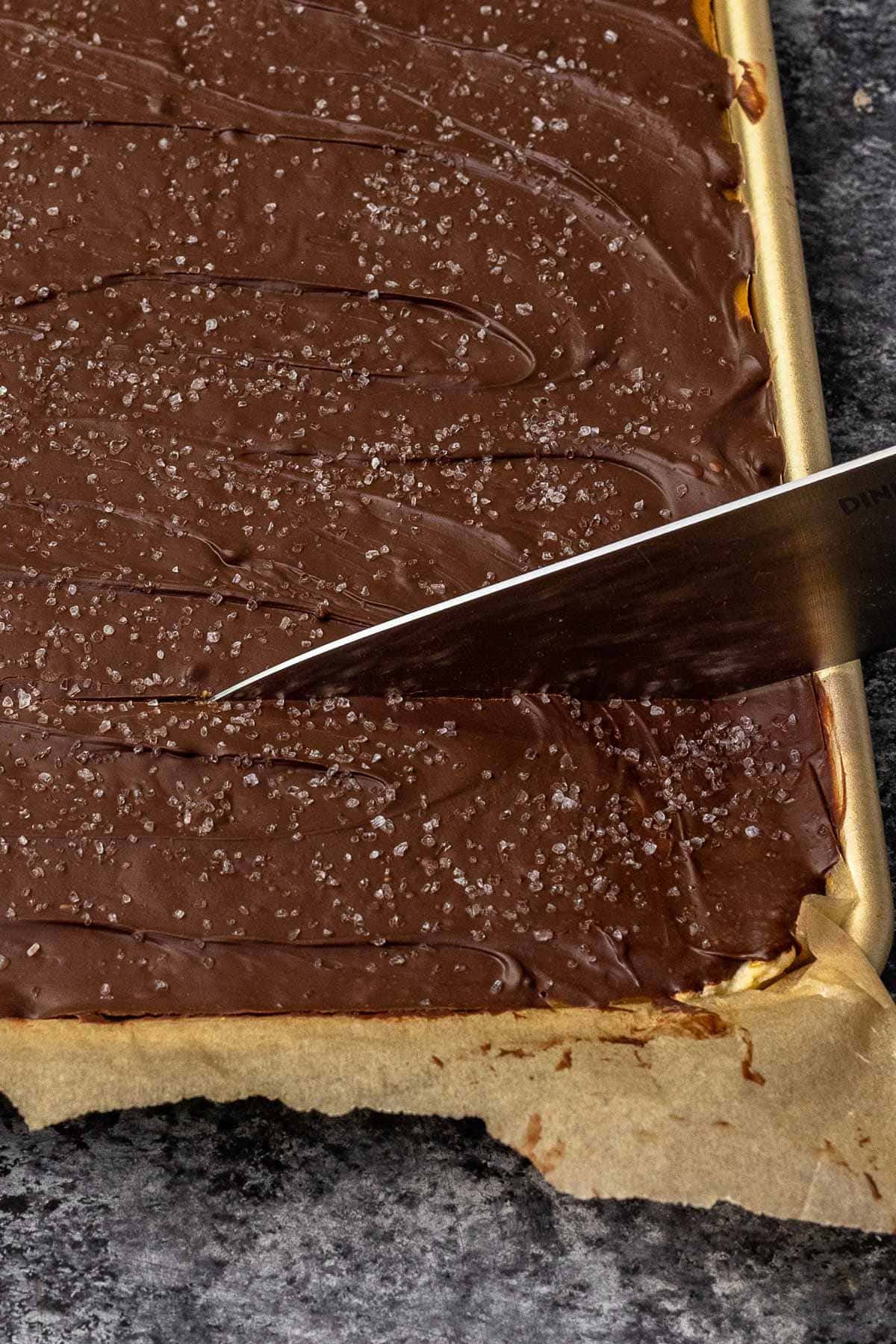 Salted Toffee Cookie Bars in pan being cut after cooling