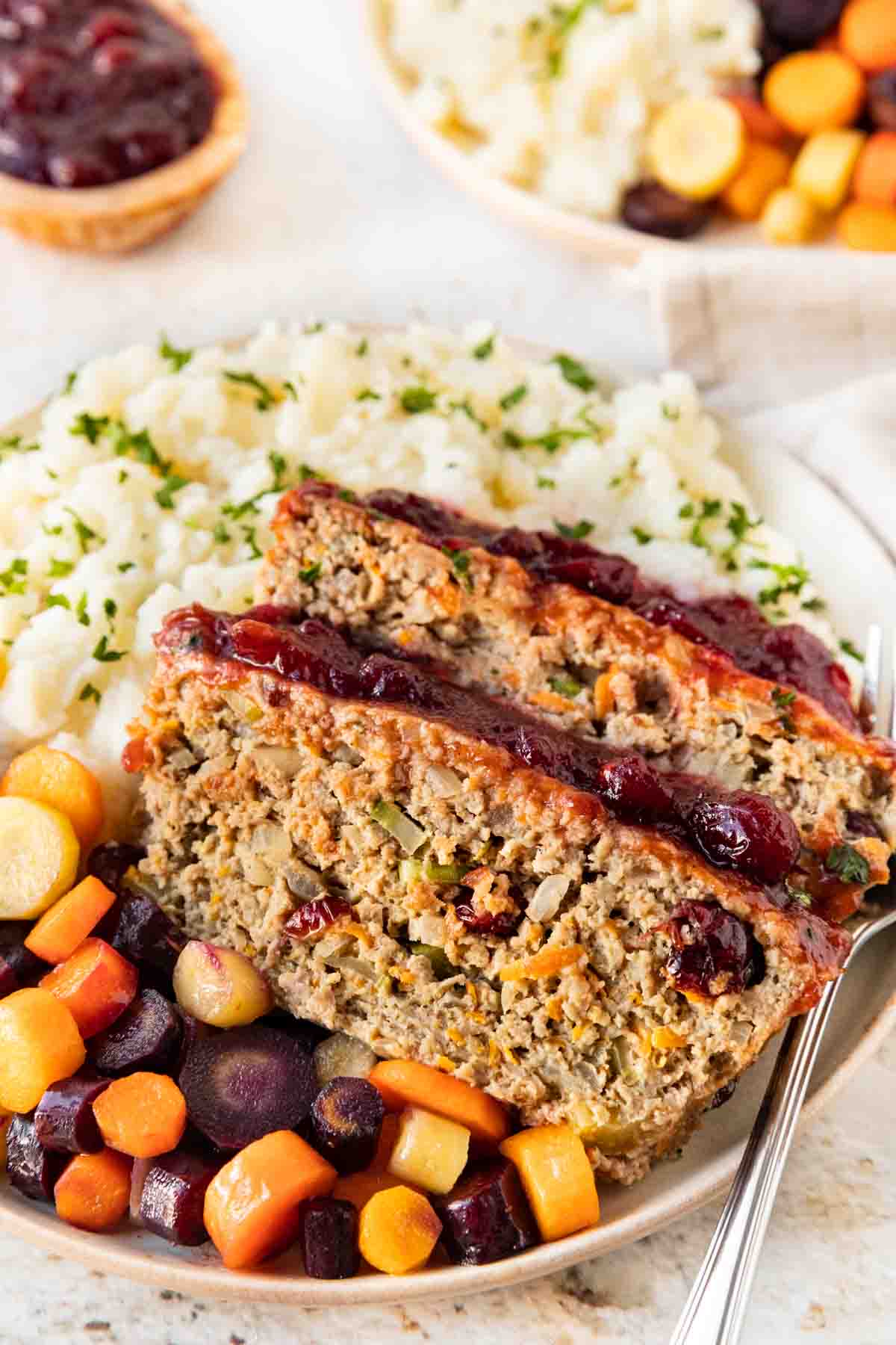 Thanksgiving Turkey Meatloaf slices in bowl with mashed potatoes and root vegetables
