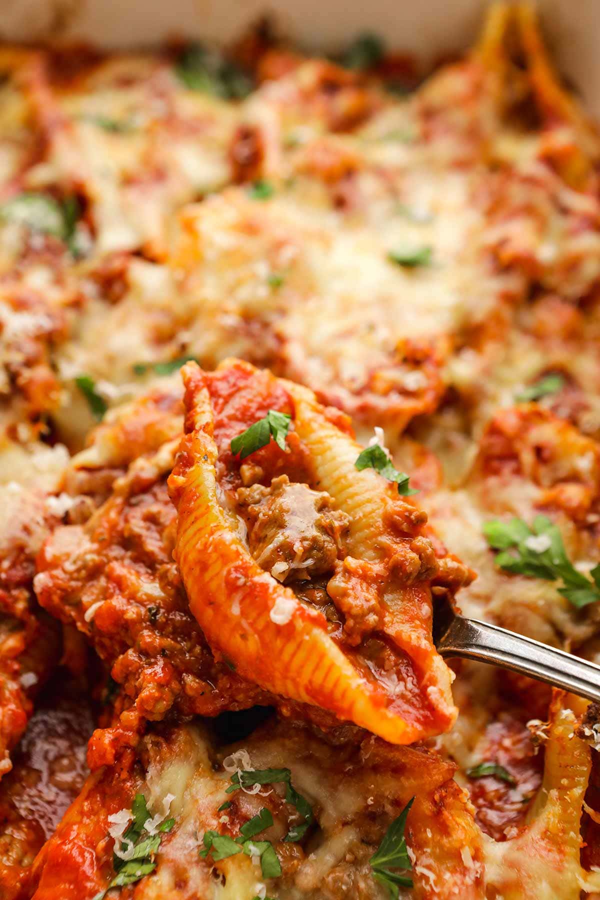 Beefy Italian Stuffed Shells spoon scooping shell from baking dish