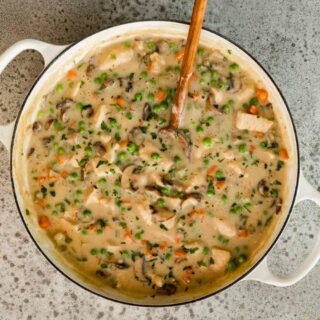 Cooked chicken and sauce in pan with spoon