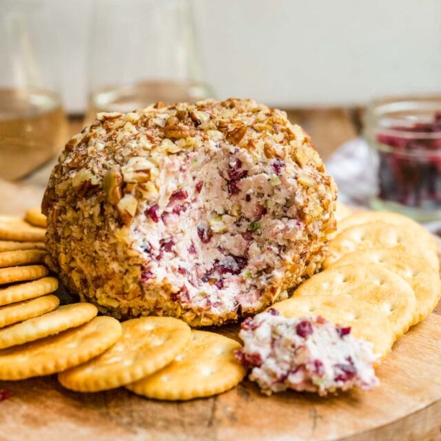 Cranberry Pecan Cheese Ball on serving tray with crackers and cut open