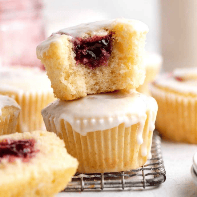 jelly doughnuts stacked on wire rack with bites taken