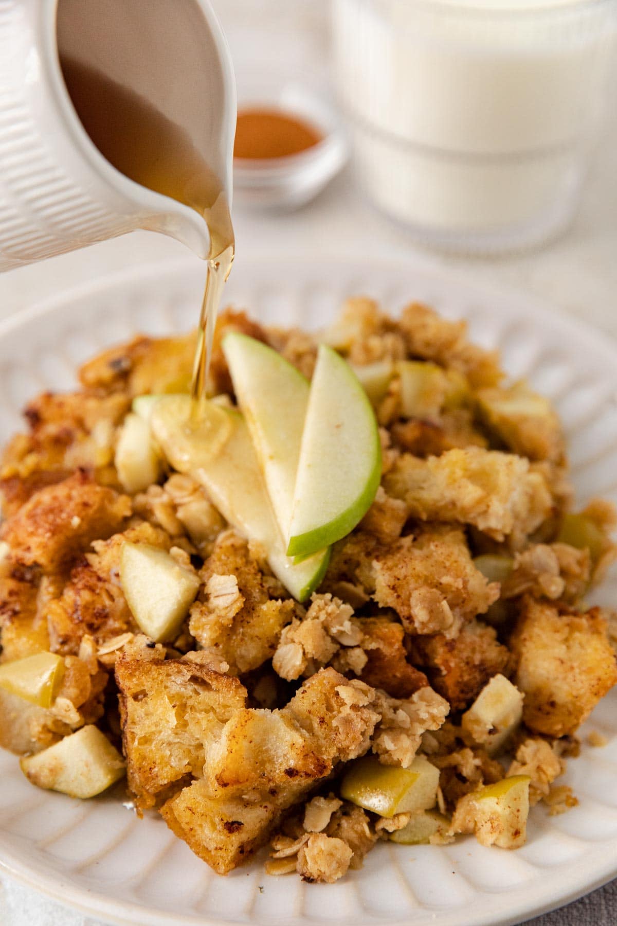 Apple Crisp French Toast Bake serving on a plate with apple slices on top and pouring syrup