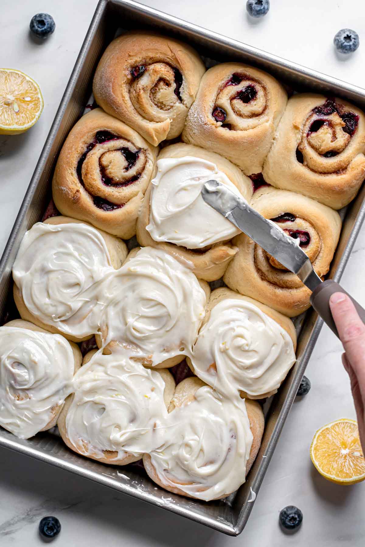 Blueberry Lemon Cinnamon Rolls frosting baked rolls in pan