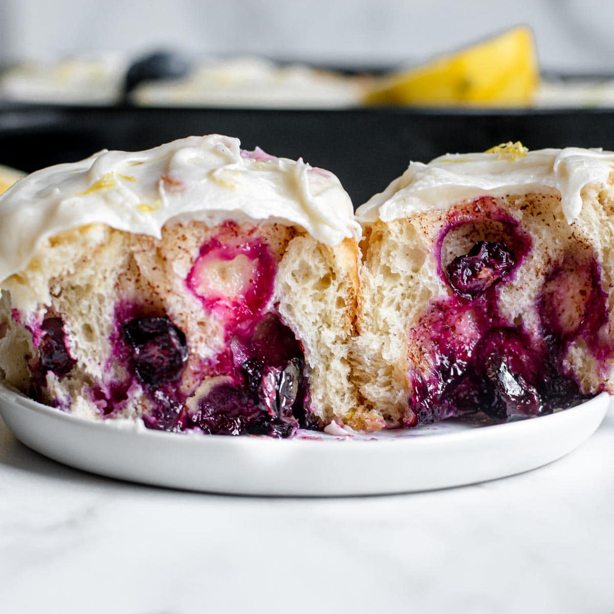 Blueberry Lemon Cinnamon Rolls single roll cut in half on plate side view