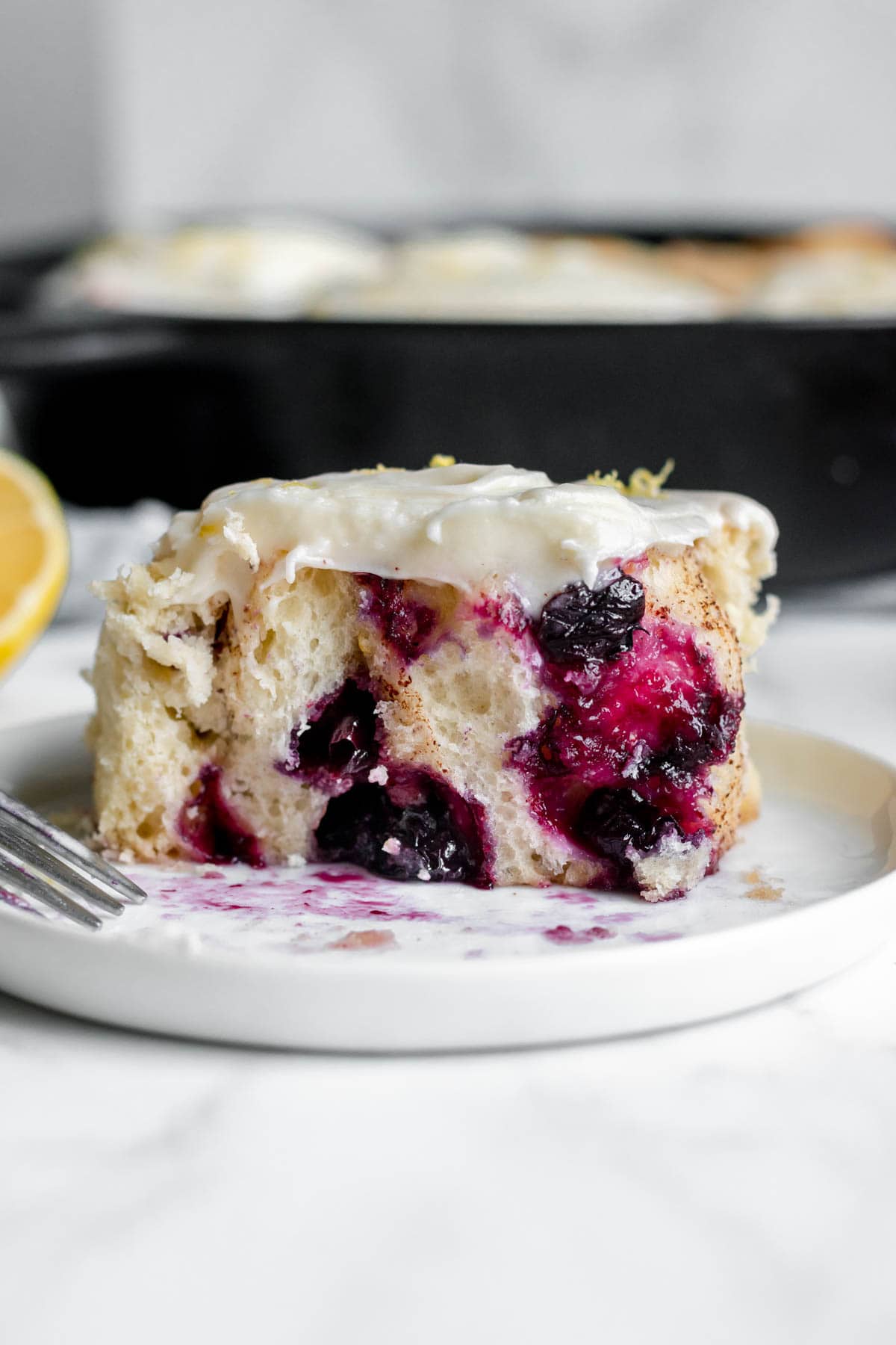 Blueberry Lemon Cinnamon Rolls single roll cut in half on plate side view