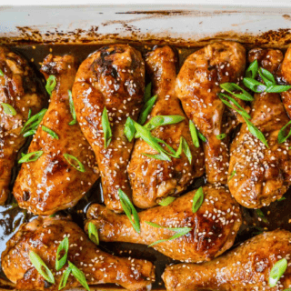 cooked poultry lined up in pan with green garnish and sesame seeds